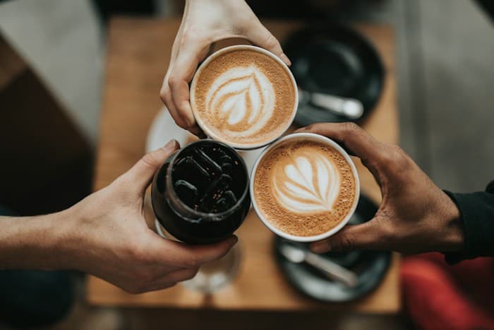 Amigos brindando com três xícaras de café em uma cafeteria